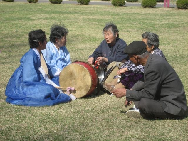 Vanhukset rentoutuvat Pjongjangin puistossa, soittavat perinteisiä soittimia ja tanssivat eläkepäiviensä ratoksi.