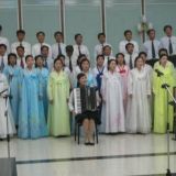Pohjoiskorealaisen spa-hotellin (!) henkilökunta esittää musiikkia Kim Il Sungin kunniaksi. Turistit kuuntelivat esitystä kiltisti. Naisilla on päällään kansallispuvut.