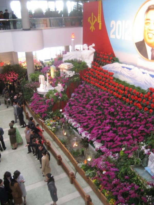Kim Il-Sungin syntymäpäivän kunniaksi järjestetyssä kukkanäytteyssä oli esillä pääasiassa kahta lajiketta: Kimilsungia-orkideoja (kuvan violetit kukat) ja Kimjongilia-begonioita (punaiset kukat). Paikalliset kuvauttivat itsensä kukka-asetelmien edess