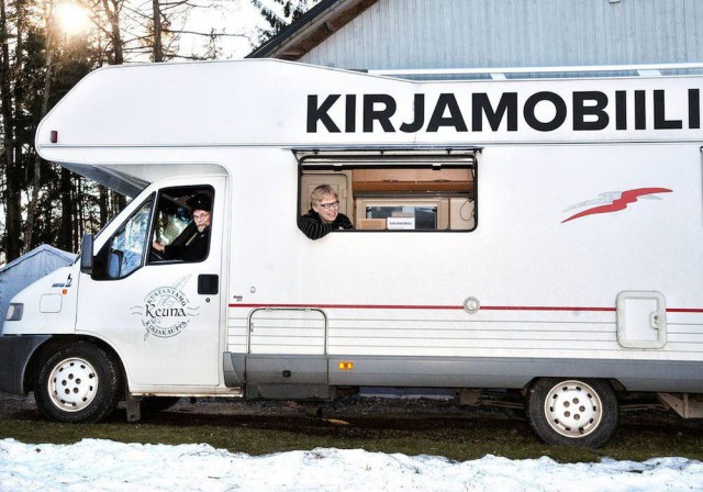 Kirjamobiili on jo liikenteessä, vaikka lumi on maassa. Kuljettajana Göran Tornaeus, kirjakaupan ikkunassa kustantaja Tarja Tornaeus.