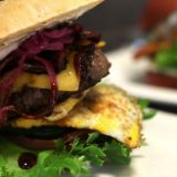Uudistuneesta house burgerissa on BBQ-kastiketta, cheddarjuustoa, paistettu luomumuna, marinoitua pekonia, sipulia ja mummonkurkkua.
